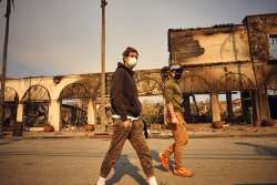 Two unidentified men walk through a fire scarred area of Pacific Palisades on Jan. 10, 2025